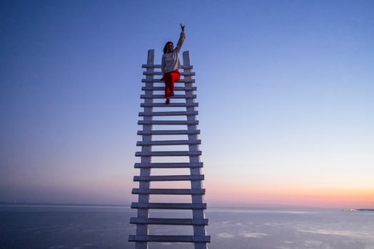 An attractive woman is laughing and sitting at the top of a wooden staircase outdoors photo