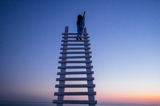 An attractive Asian woman is laughing and sitting at the top of a wooden staircase outdoors photo
