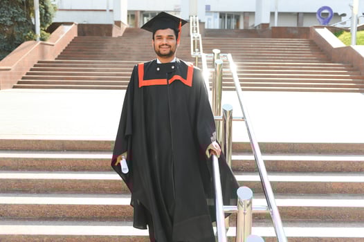 Handsome indian graduate in graduation glow with diploma photo