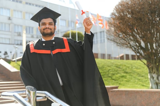 Handsome indian graduate in graduation glow with diploma photo