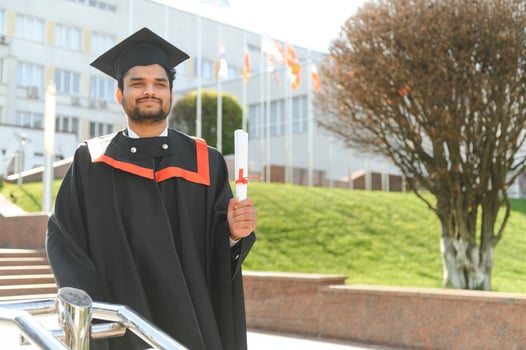 Handsome indian graduate in graduation glow with diploma photo