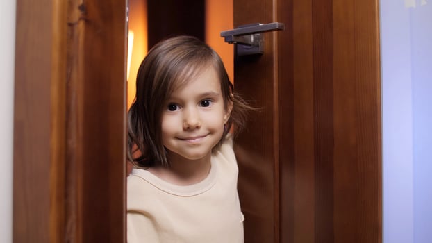portrait Little girl with black eyes opening a door and looking at camera photo