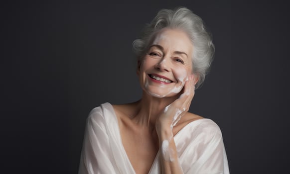 Elderly woman applies facial cream, gracefully embracing a skincare routine photo