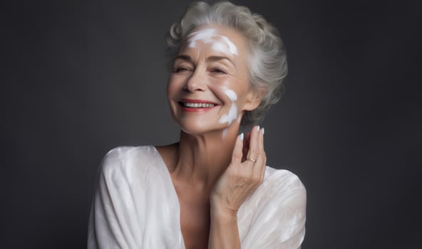 Elderly woman applies facial cream, gracefully embracing a skincare routine photo