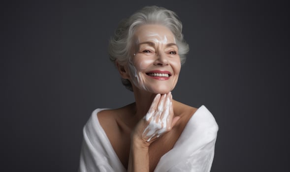 Elderly woman applies facial cream, gracefully embracing a skincare routine photo