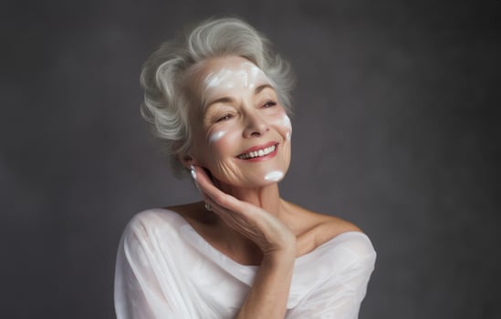 Elderly woman applies facial cream, gracefully embracing a skincare routine photo