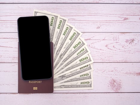 Top view of smartphone and passport book with US dollars banknote on wooden table photo