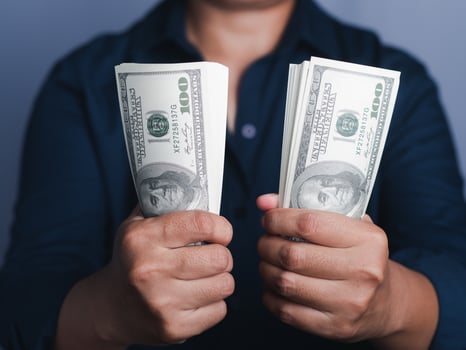 Hands holding of a US dollars banknote with a gray background while standing in the studio. Close-up photo. Space for text photo