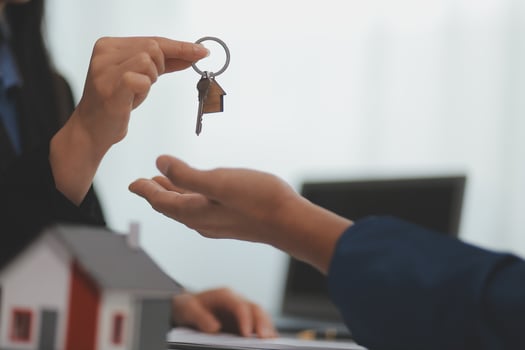 Estate agent giving house keys to client after signing agreement contract real estate with approved mortgage application form, concerning mortgage loan offer for and house insurance. photo