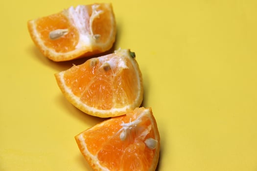 Sliced juicy orange fruit on yellow photo