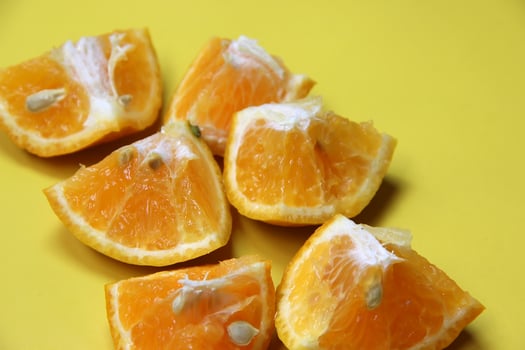 Sliced juicy orange fruit on yellow photo
