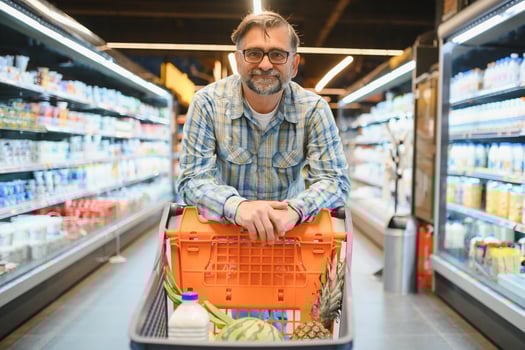 Mature man pushing a shopping cart at the supermarket, he is buying groceries, grocery shopping concept photo