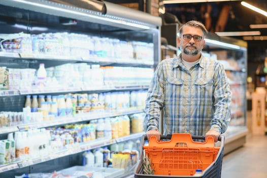 Mature man pushing a shopping cart at the supermarket, he is buying groceries, grocery shopping concept photo