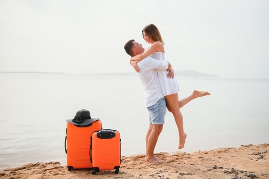 Young couple with suitcase on the beach in summer day. The concept of recreation at sea and travel photo