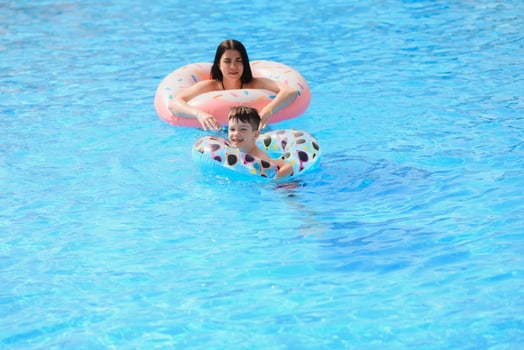 Happy child and woman playing in swimming pool. Summer vacation concept photo