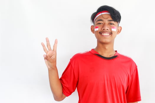 A confident young Asian man makes a number sign on an isolated white background. wearing a red shirt. Indonesian Independence day photo