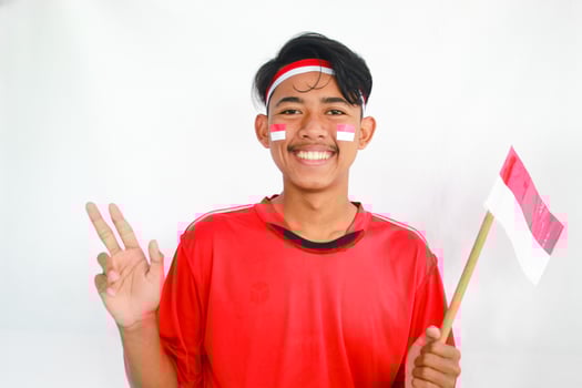 A confident young Asian man makes a number sign on an isolated white background. wearing a red shirt. Indonesian Independence day photo