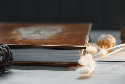 Family photo book with embossing. Photo book on a wooden background. Brown photo book with wood cover. Photoalbum with a hard cover. Wedding photo album.
