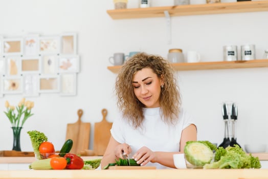 Happy young housewife mixing vegetable salad photo