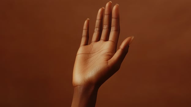 A Close-Up View of an Upward Reaching Hand Against a Warm Brown Background in Soft Natural Light photo
