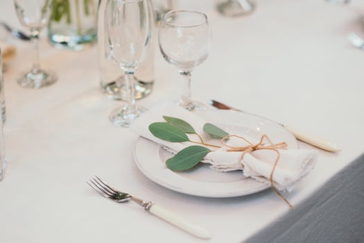 Table setting with napkin on empty white plate, wineglasses and cutlery on table, copy space. Place setting at wedding reception. Table served for banquet photo