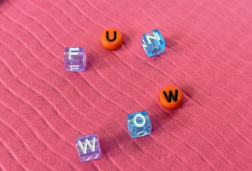 The word fun spelled with an orange cube on a pink background photo