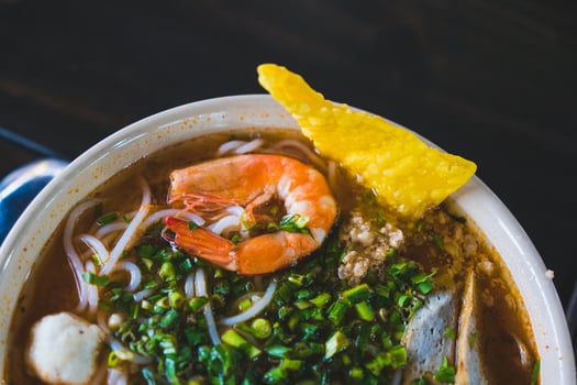 Tom Yum soup - Thai soup with prawns and rice noodles on wooden table in Vietnam photo