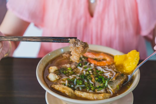 Tom Yum soup - Thai soup with prawns and rice noodles on wooden table in Vietnam photo