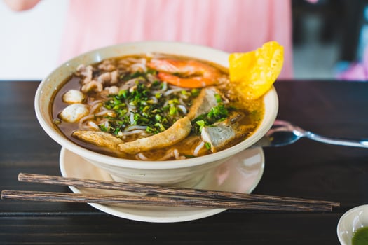 Tom Yum soup - Thai soup with prawns and rice noodles on wooden table in Vietnam photo
