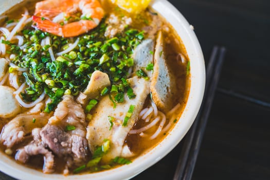 Tom Yum soup - Thai soup with prawns and rice noodles on wooden table in Vietnam photo