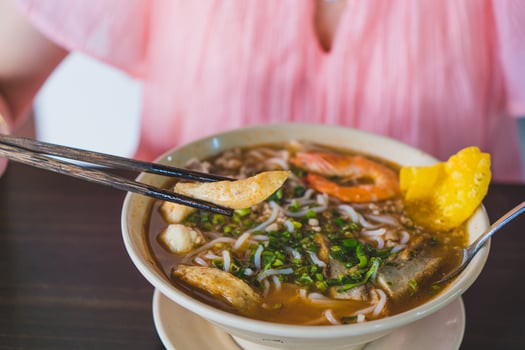 Tom Yum soup - Thai soup with prawns and rice noodles on wooden table in Vietnam photo