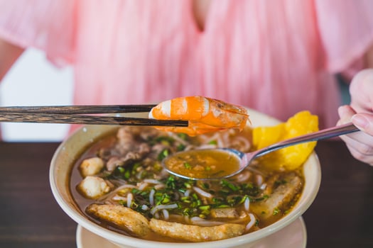 Tom Yum soup - Thai soup with prawns and rice noodles on wooden table in Vietnam photo