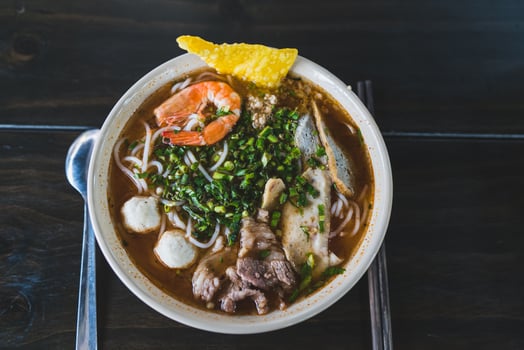 Tom Yum soup - Thai soup with prawns and rice noodles on wooden table in Vietnam photo