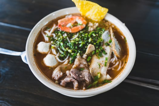 Tom Yum soup - Thai soup with prawns and rice noodles on wooden table in Vietnam photo