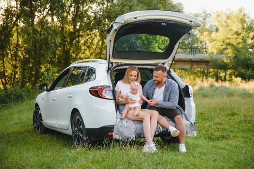 Family with kid sitting in car trunk photo