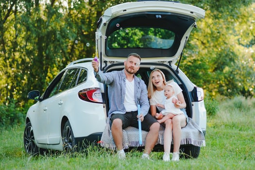 Young family three people in white clothes have picnic. Beautiful parents and daughter travel by car during summer vacation. Scene in park photo