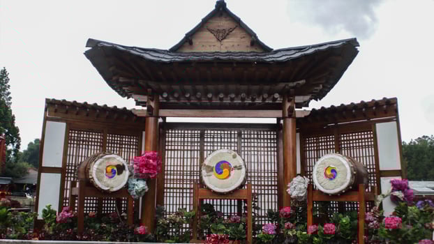 Traditional Korean Pavilion with Colorful Drums and Lattice Background Surrounded by Vibrant Flowers photo