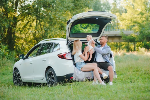 Happy family near car trunk on sunny day. Road trip photo