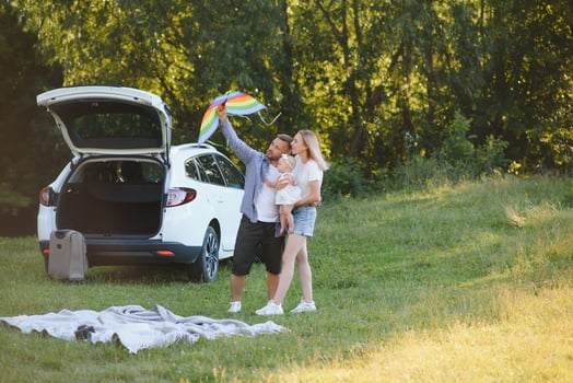 Young family three people in white clothes have picnic. Beautiful parents and daughter travel by car during summer vacation. Scene in park photo