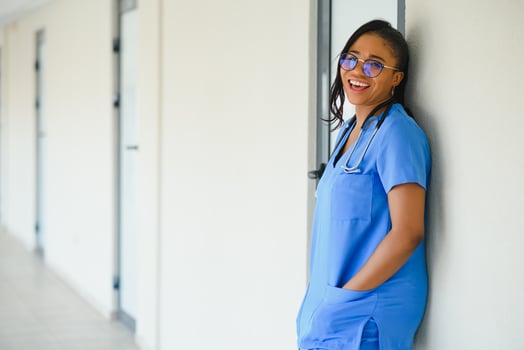 Portrait confident African American female doctor medical professional writing patient notes isolated on hospital clinic hallway windows background. Positive face expression photo
