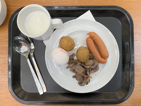 Healthy Breakfast food include sausage, potato, boiled egg, mushroom in a white plate and a cup of milk with black tray photo