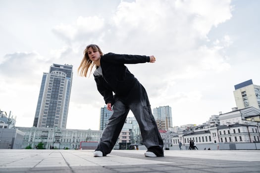 Young Dancer Performing Urban Dance Moves in Downtown Area Under Dramatic Sky photo