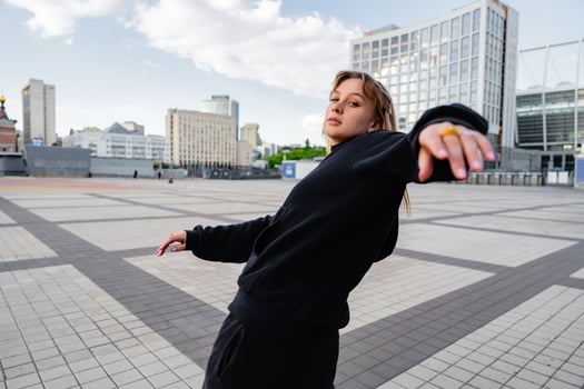 Young Woman Engaging in Dynamic Dance Movement in Urban City Square During Daylight photo