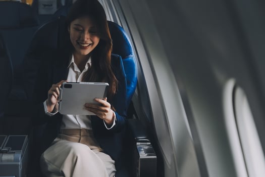Young Asian executive excels in first class, multitasking with digital tablet, laptop and smartphone. Travel in style, work with grace. photo