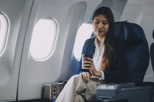 Young Asian female tourist traveling alone on a plane is drinking hot coffee and looking out the window. photo