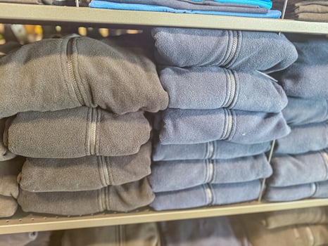 mens black and blue fleece jackets in stack in the shop . High quality photo