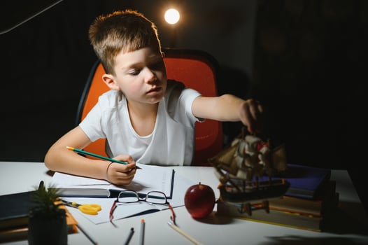 Little boy painting in a dark room late in the evening photo
