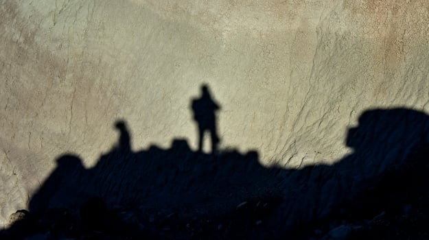 Shadow of a man against a background of dry cracked clay, cracks on the ground. photo