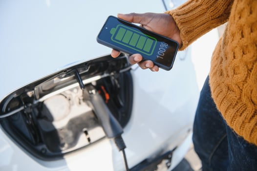 Smartphone app shows charging status of the electric car battery. Electro transport concept photo