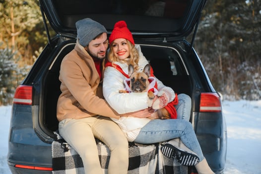 couple guy and girl sitting in car playing with dog in winter forest photo